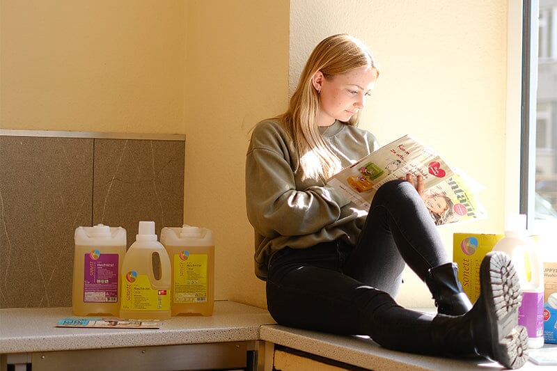 Model liest Magazin, nachhaltige Reinigungsprodukte von Sonett stehen neben ihr