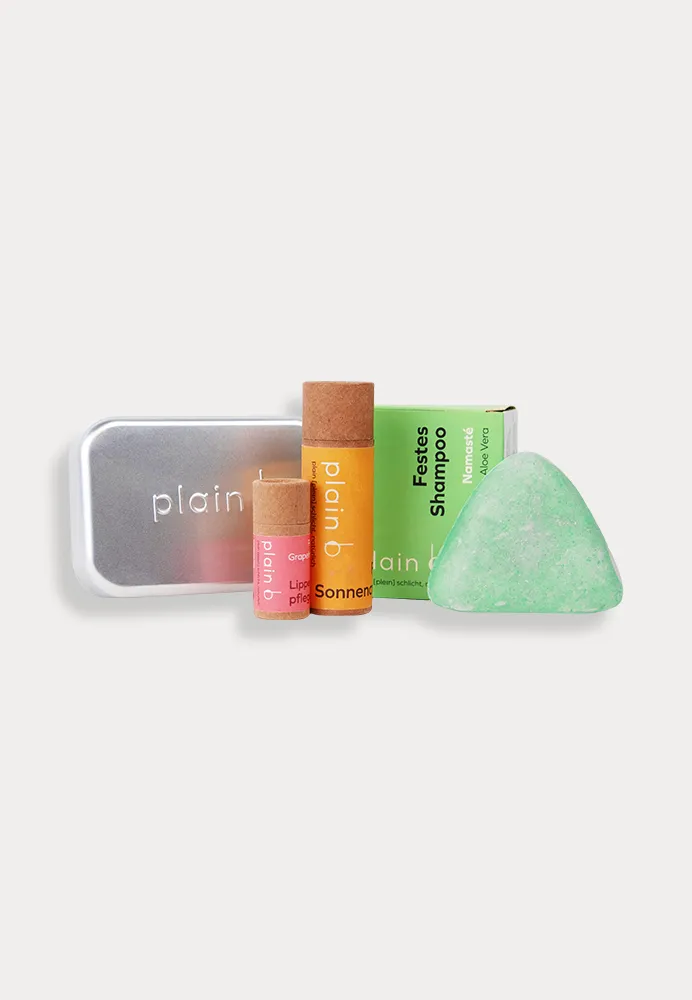 Kleines Reise-Set von plain b bestehend aus einem festen Shampoo Kokos Aloe Vera, einer Lippenpflege Granatapfel, einer festen Sonnencreme und einer Seifendose